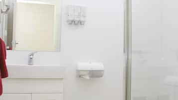 A modern bathroom with a white sink, mirror, and glass shower enclosure.