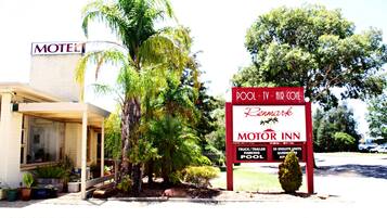 Un motel con un letrero que dice Motor Inn, que ofrece comodidades como piscina, televisión, aire acondicionado y estacionamiento.