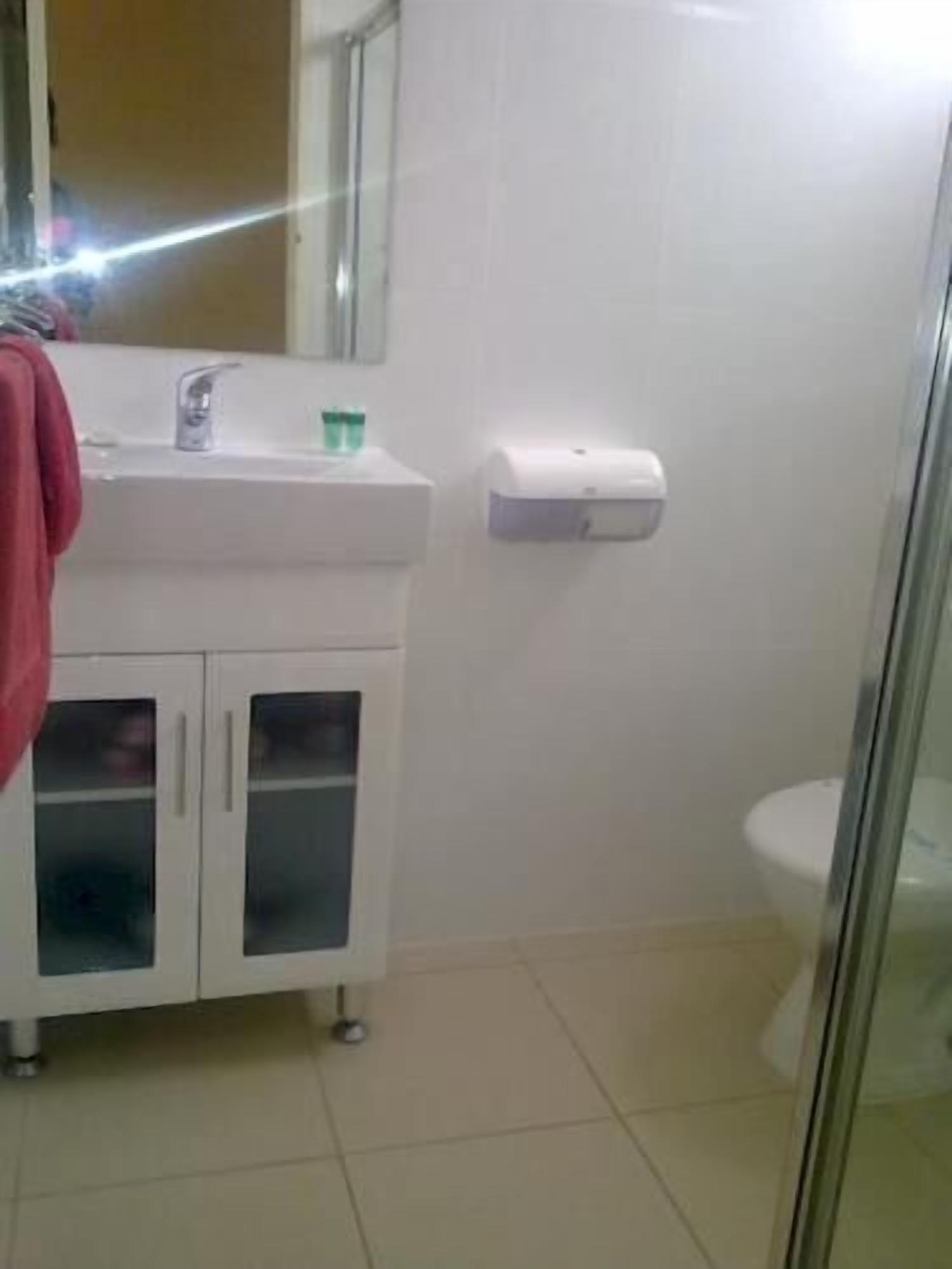 Een badkamer met een witte wasbak, spiegel en toilet.