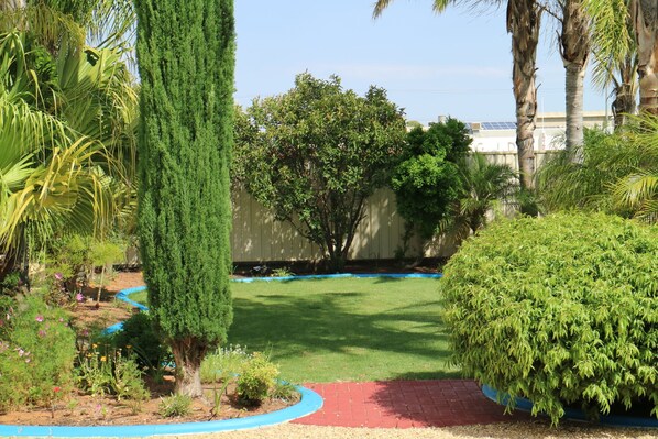 Un jardín bien cuidado con diversas plantas y un césped impecable.