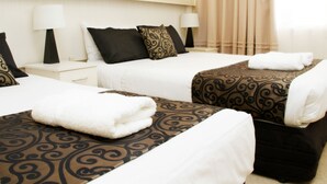 A hotel room with two beds, each with a patterned bedspread and white linens. There are two bedside tables with lamps, and a window with curtains. - Renmark Motor Inn Motel (Renmark)