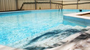 A swimming pool with clear water, steps leading into the pool, and a tiled edge.