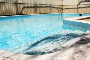 A swimming pool with clear water, steps leading into the pool, and a tiled edge.