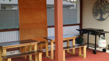Un patio cubierto con bancos de madera y una parrilla.
