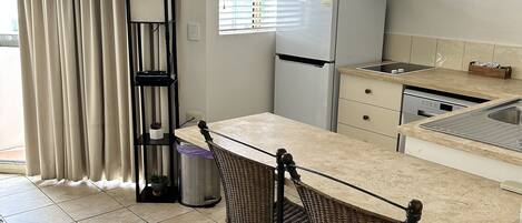Una cocina compacta con comedor, que incluye un refrigerador empotrado, una estufa y un lavamanos.