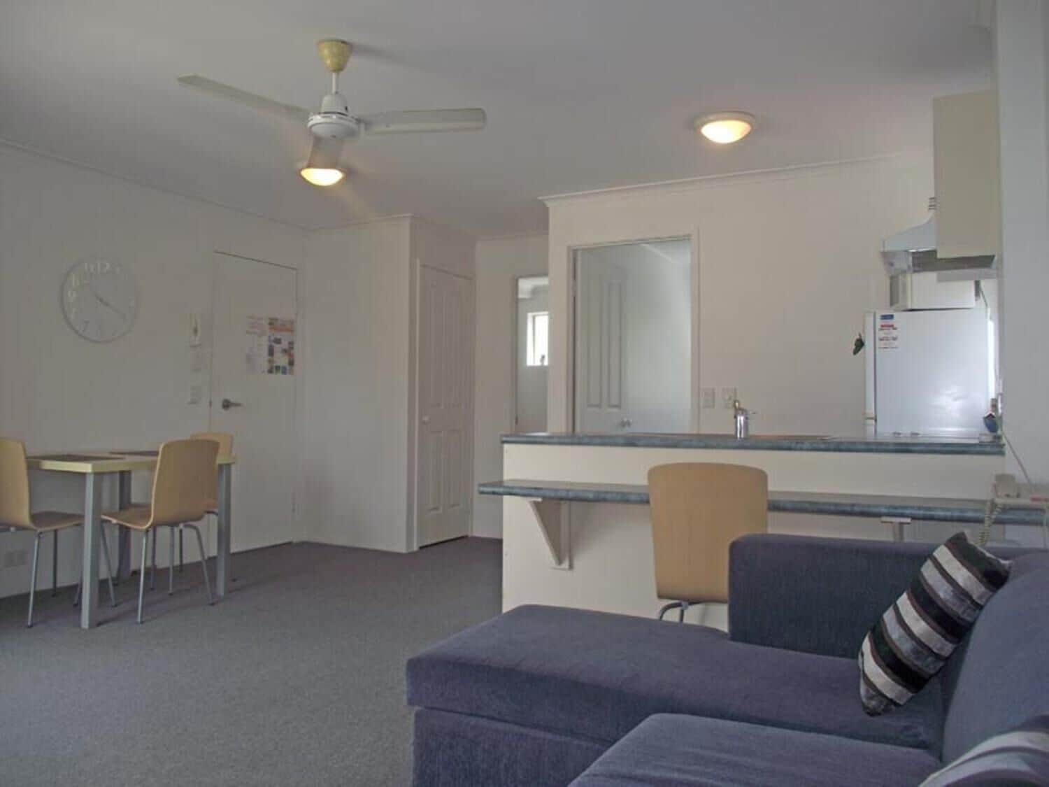 A compact living space with a kitchenette, a dining area, and a seating area with a sofa and chairs.