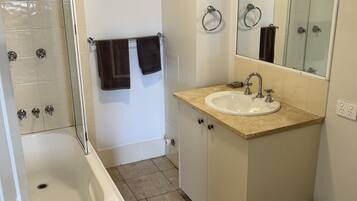 A bathroom with a bathtub, sink, toilet, and a glass shower enclosure.