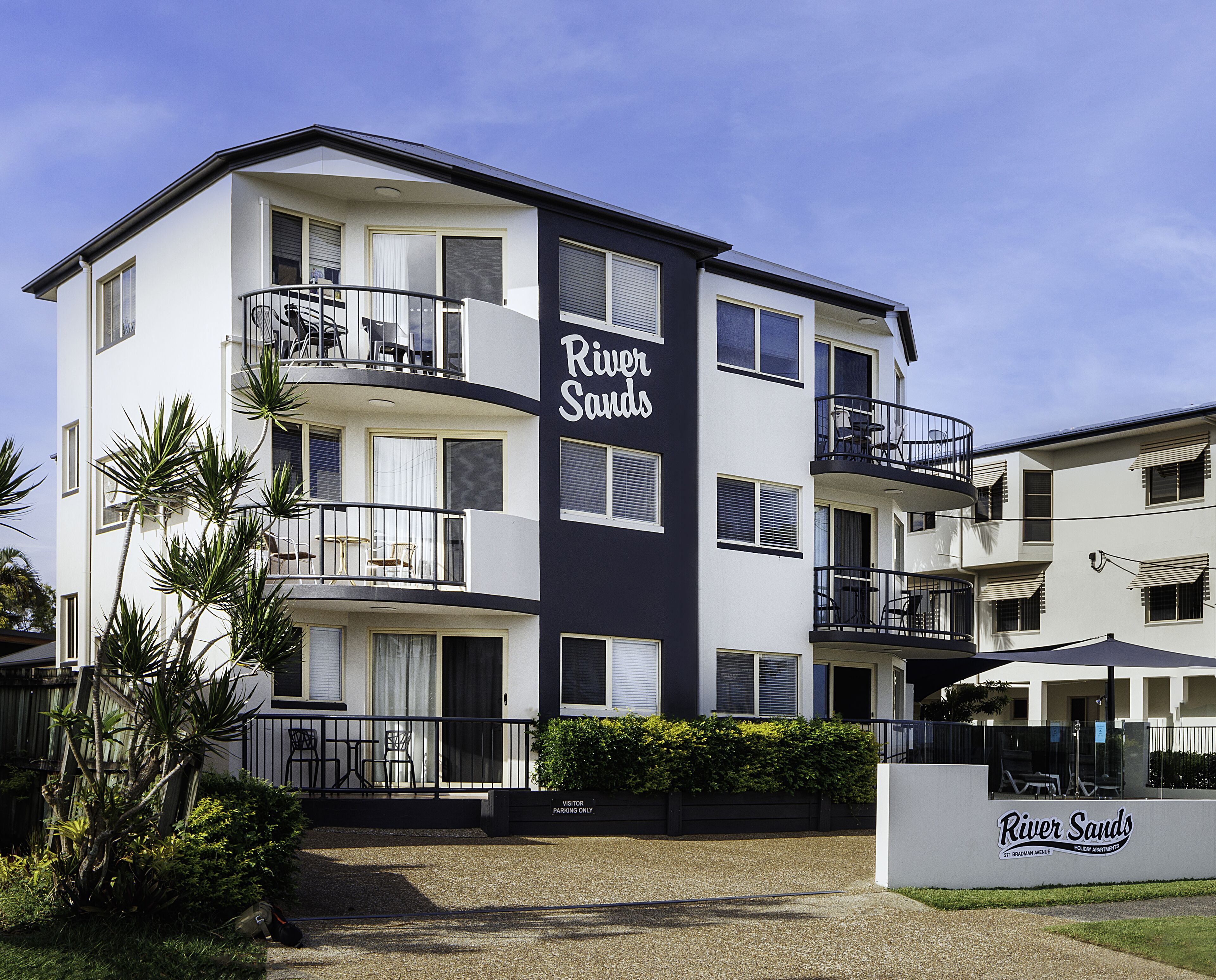 Un edificio de varios pisos con balcones y un letrero que dice 'River Sands'.