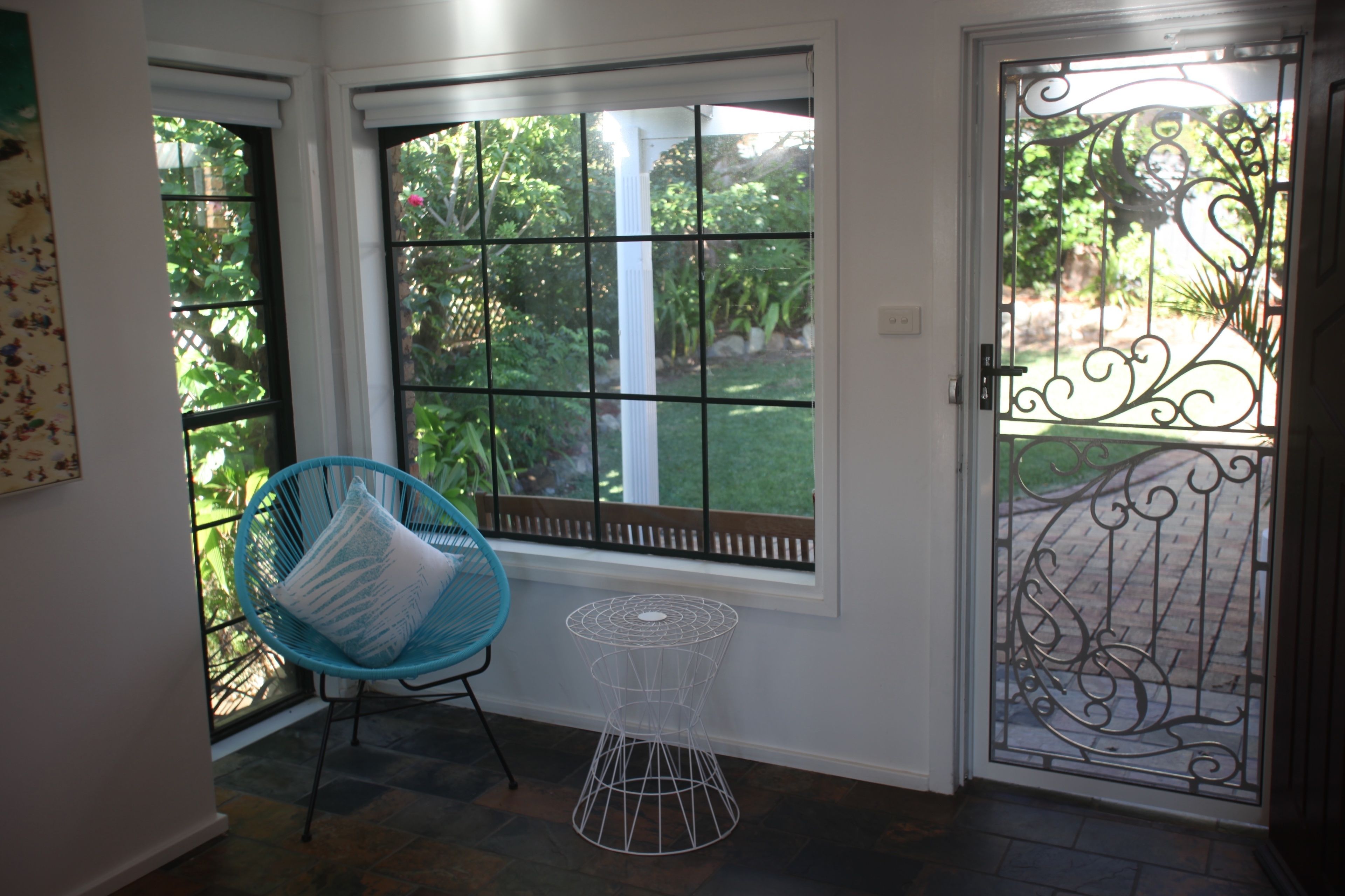 A room with a large window, a blue chair, and a decorative metal gate.