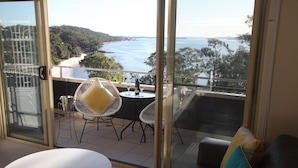 Ein Balkon mit Tisch und Stühlen, einer Couch und Blick auf Strand und Meer.