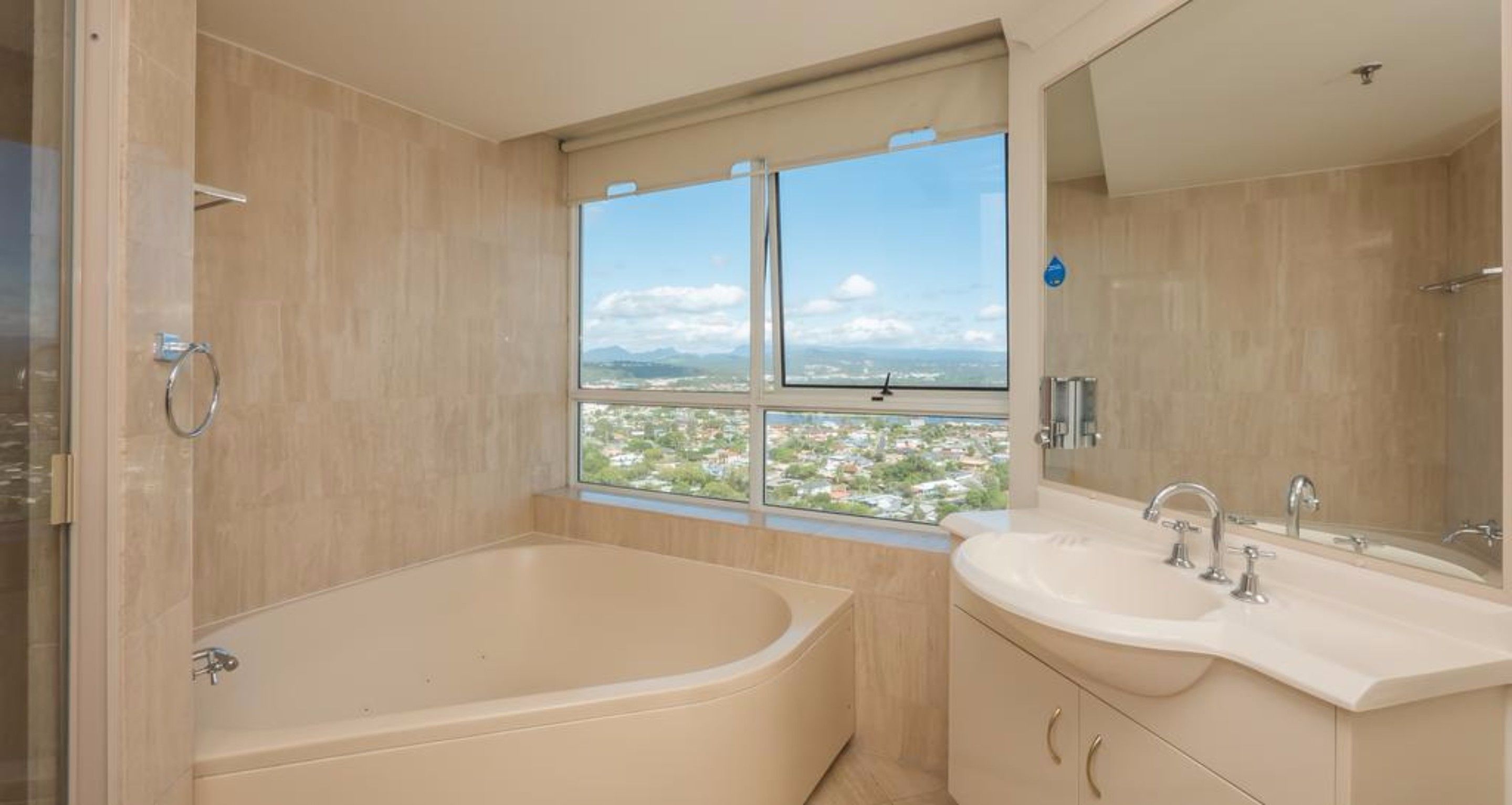 Un baño moderno con una bañera grande, dos lavamanos y un ventanal con vistas a la ciudad.