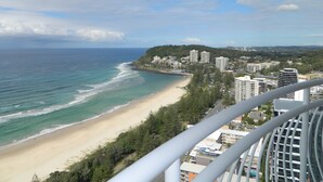 A coastal cityscape with a beach, buildings, and a forested hill. - 2nd Avenue Beachside Apartments (Burleigh Heads)