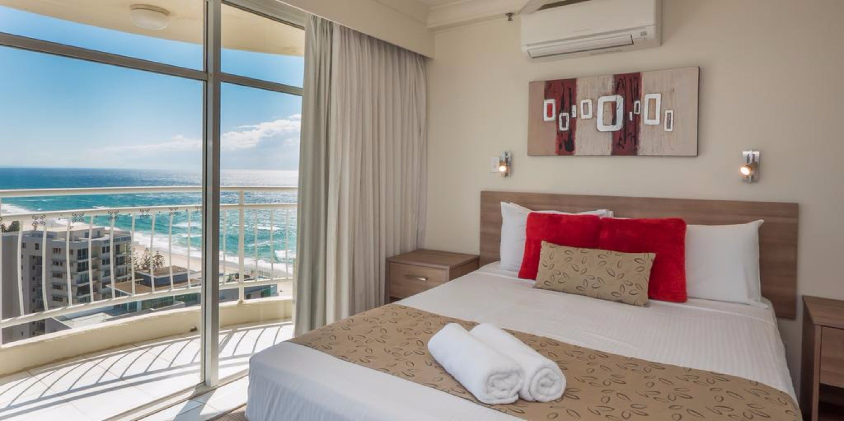 Een hotelkamer met een groot bed, uitzicht op zee en een balkon.
