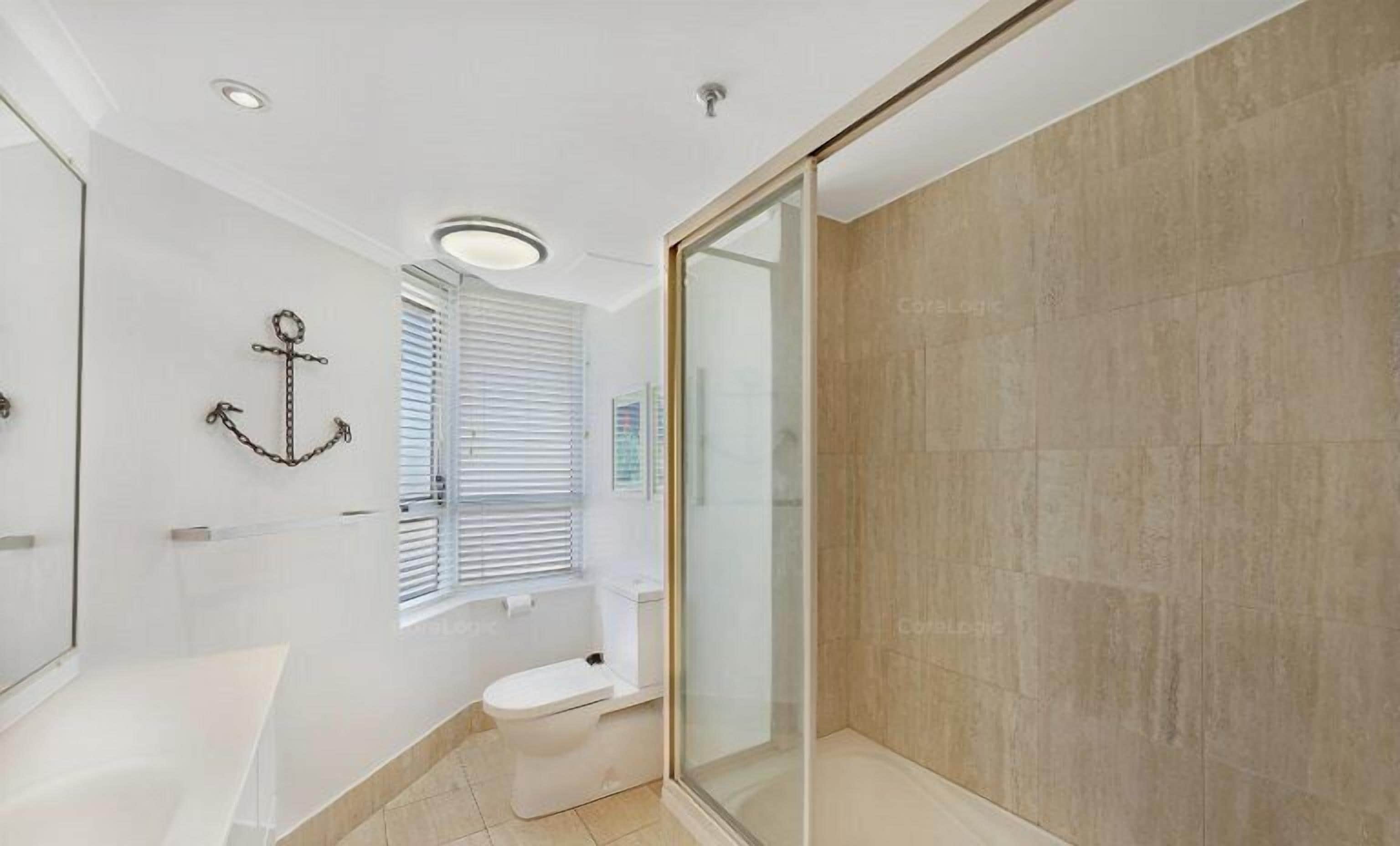 Un baño moderno con cabina de ducha de vidrio, una bañera blanca y un inodoro.