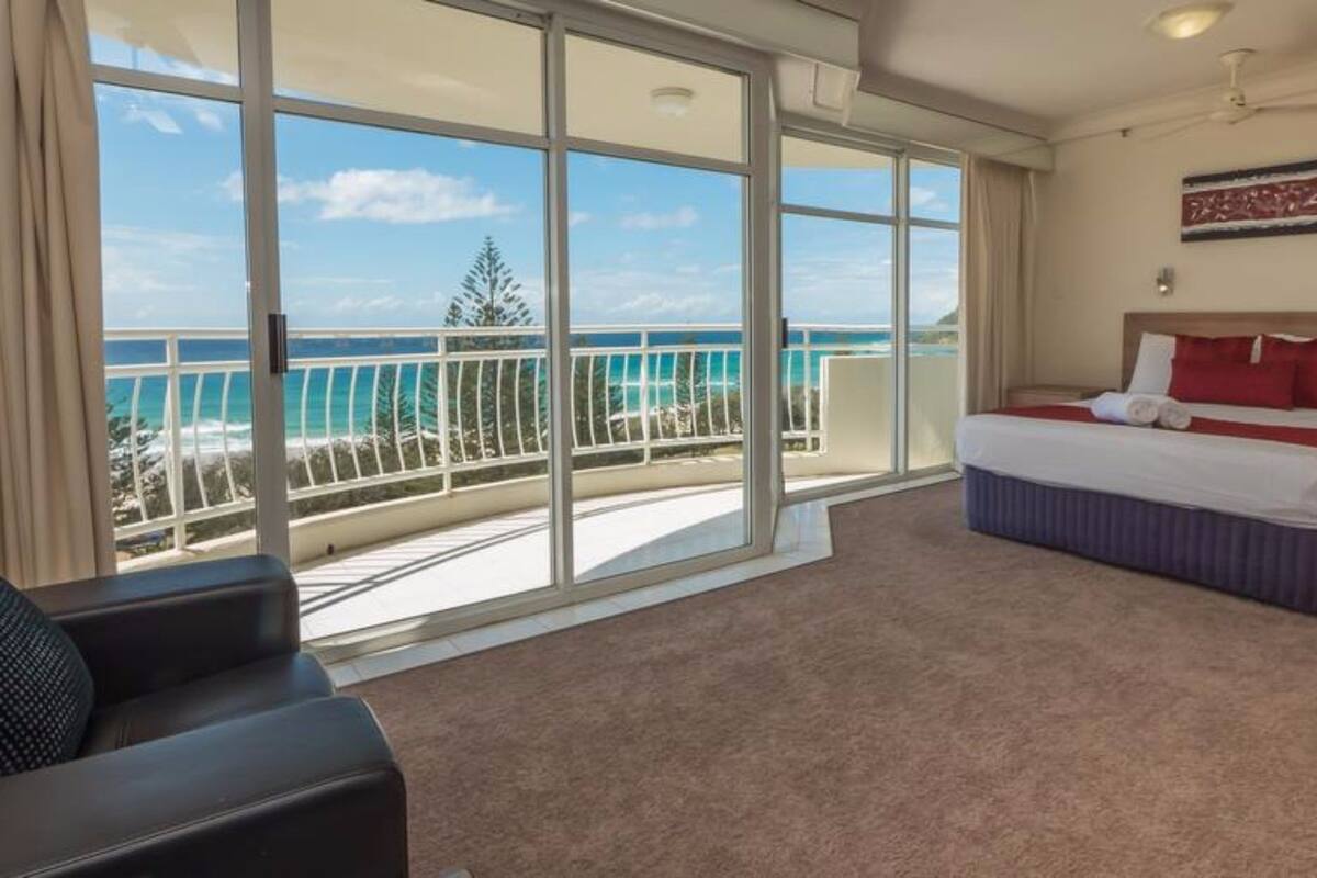 Une chambre d’hôtel dotée d’un grand balcon, d’un lit, d’un canapé et offrant une vue sur l’océan.