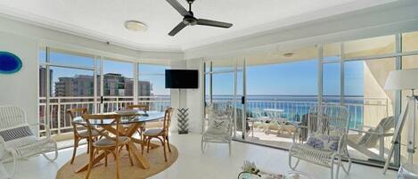 A spacious balcony with a dining area, chairs, and a ceiling fan.