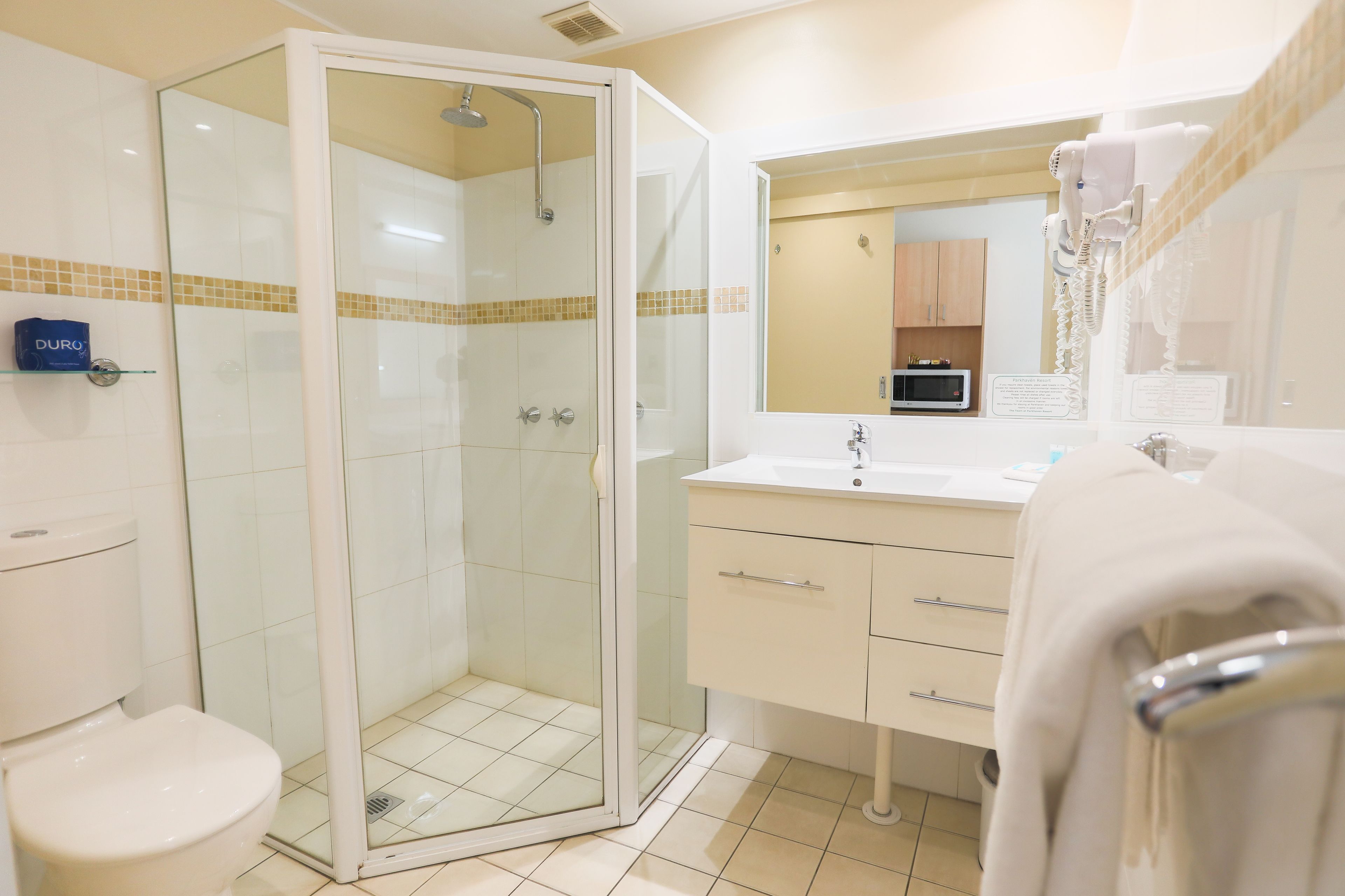 A bathroom with a glass-enclosed shower, a white sink, and a mirror above the sink.