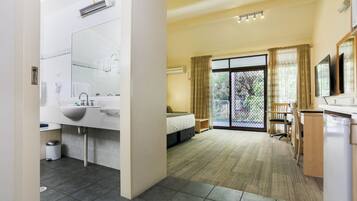 A modern hotel room with a large bathroom, a bed, a desk, and a view of the outdoors.