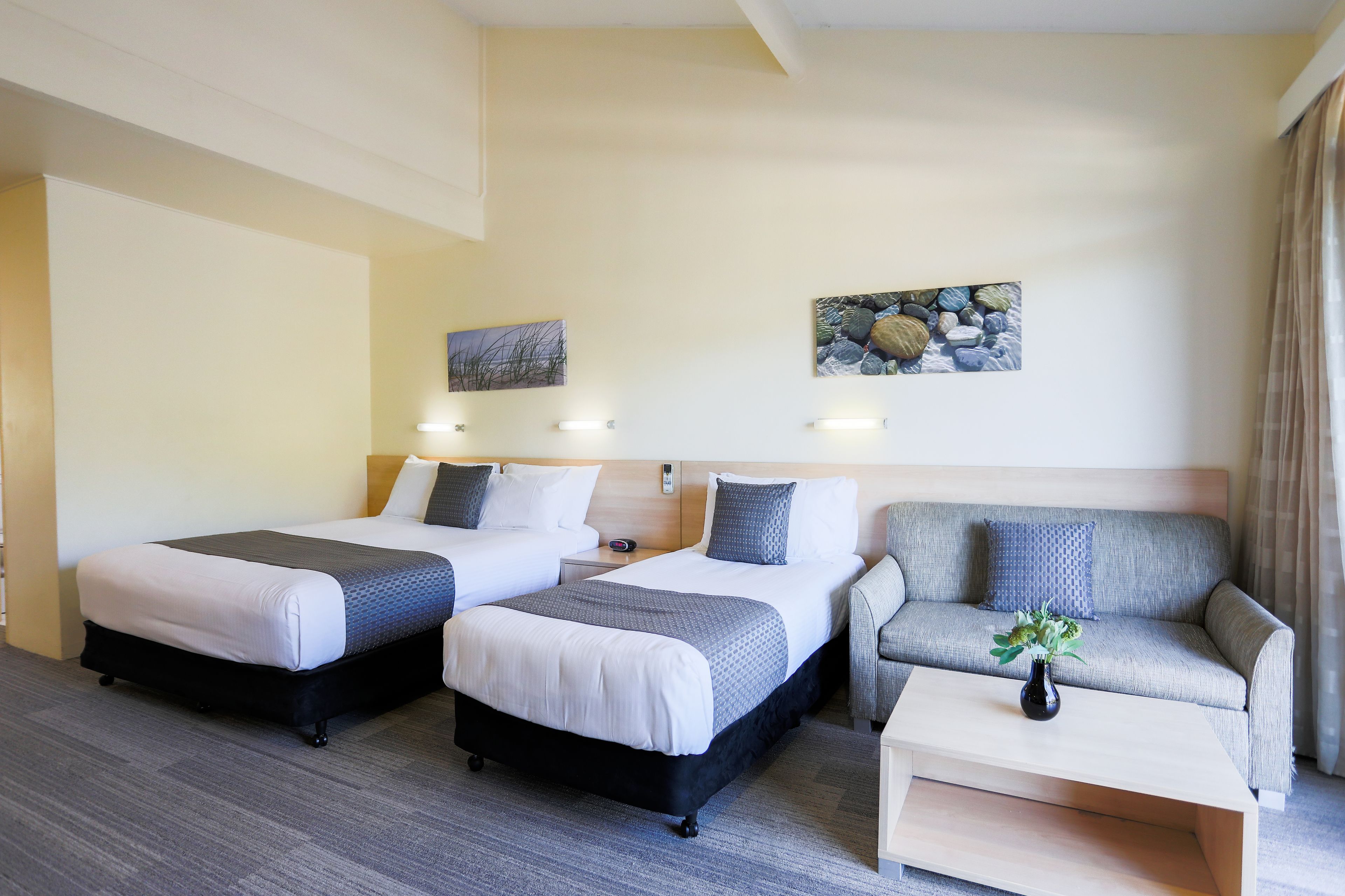 A hotel room with two beds, a sofa, and a coffee table.