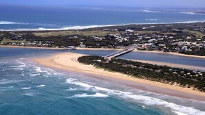 Vista aérea de uma cidade costeira com praia, um cais e áreas residenciais.