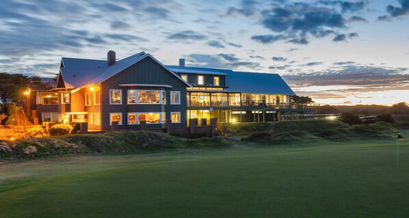 A large, modern house with multiple windows and a well-lit exterior, situated on a golf course. - Barwon Heads Golf Club (Barwon Heads)