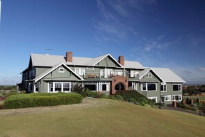 A large, two-story house with a prominent brick archway, multiple windows, and a well-maintained lawn. - Barwon Heads Golf Club (Barwon Heads)