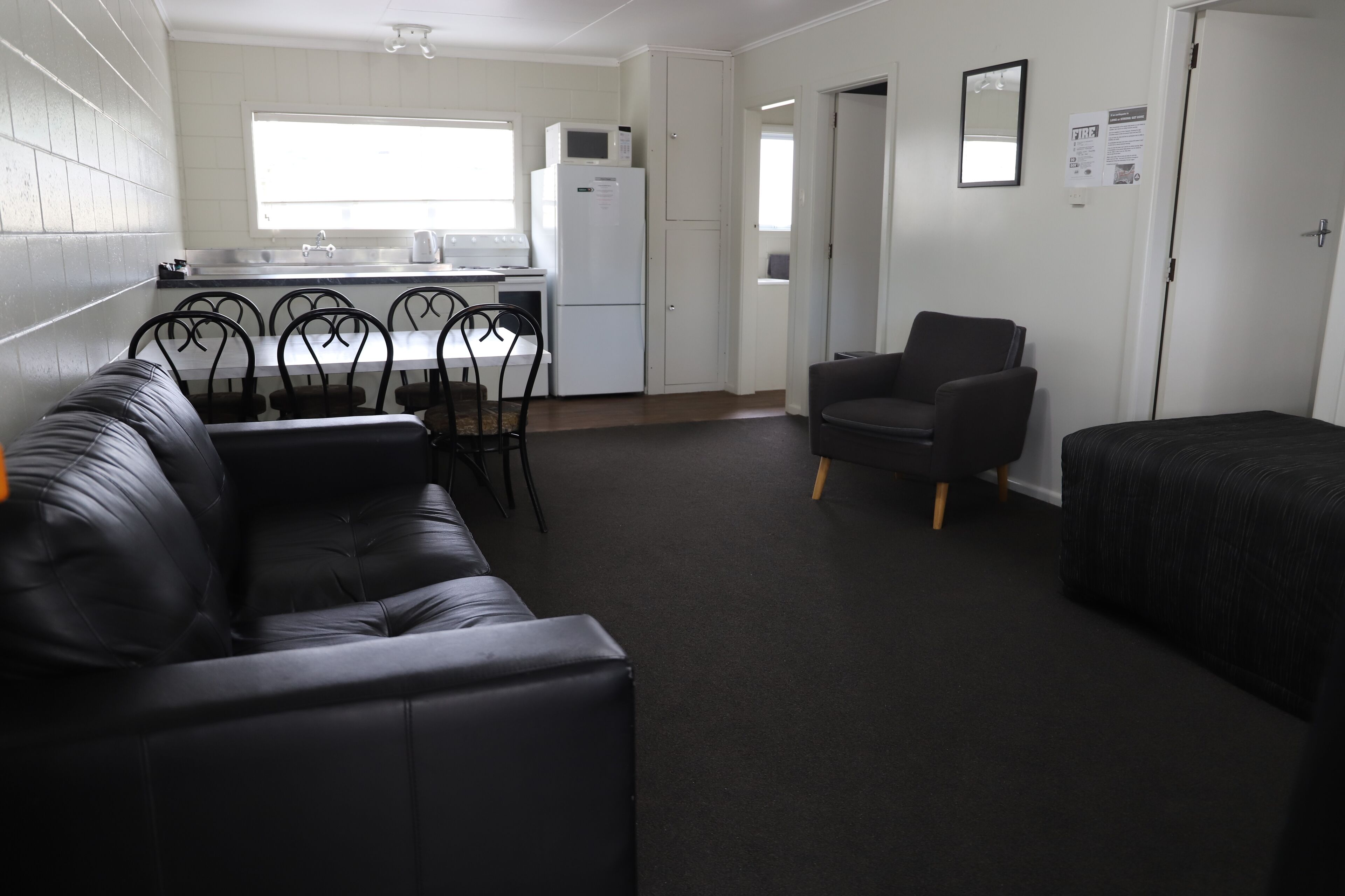 A compact living space with a kitchenette, a dining area, a sofa, and a chair.