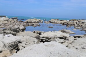 Una playa rocosa con grandes cantos rodados y agua tranquila.