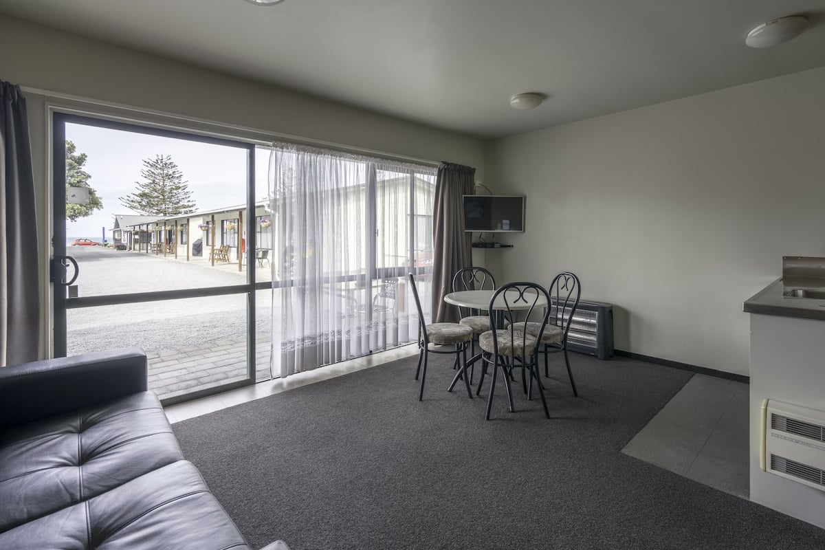 A modern room with a sofa, dining table, chairs, and a TV.