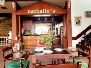 Ein Restaurantinneres mit einer Holztresen, einer grün gepolsterten Bank und einer Vase mit Blumen.