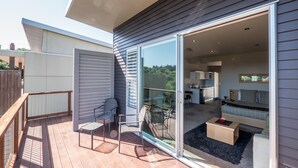 Una vivienda moderna con terraza, puertas corredizas que dan a una sala de estar con sofá y mesa de comedor.