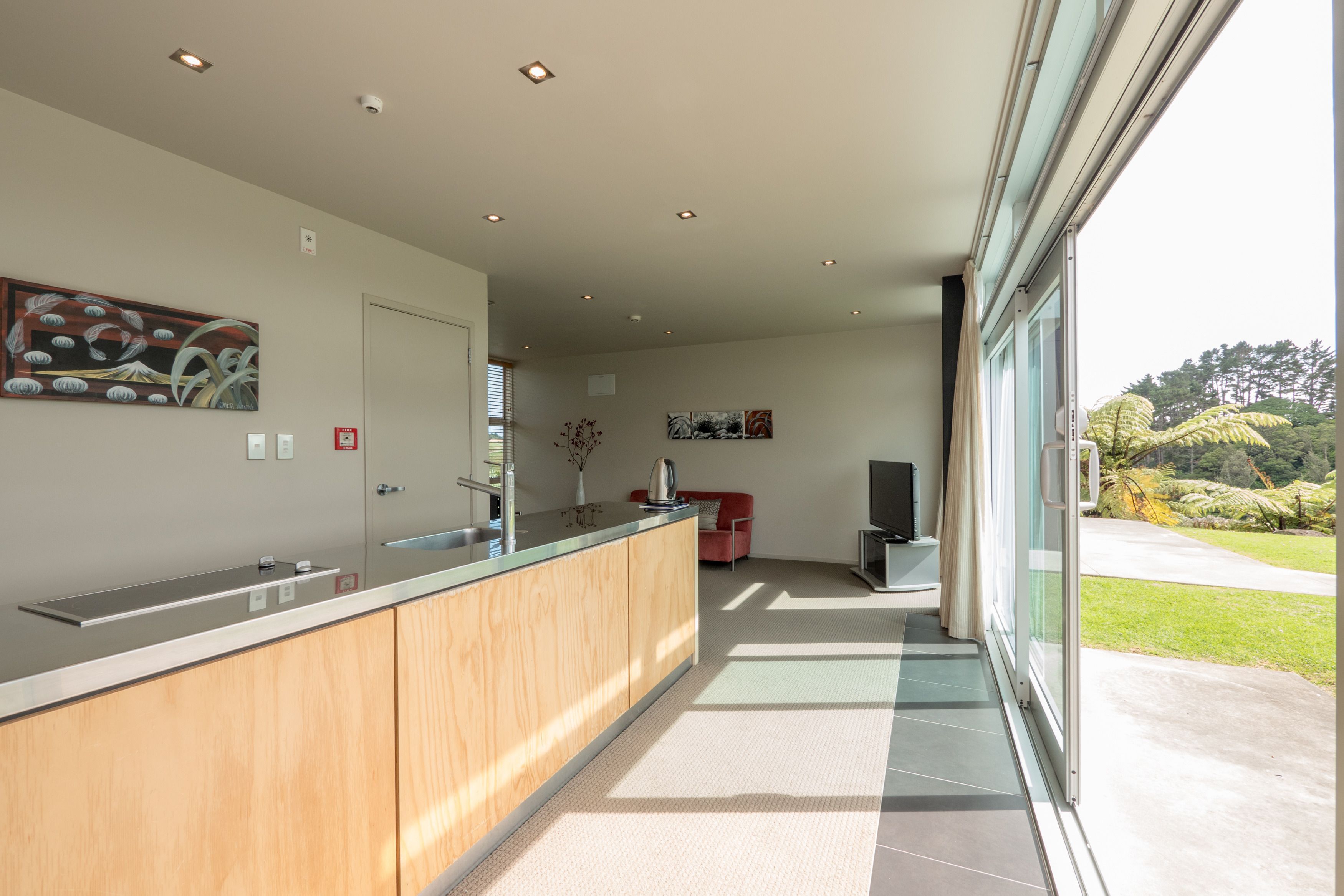 A modern kitchen with a wooden countertop, a red sofa, and a large window offering a view of the outdoors.