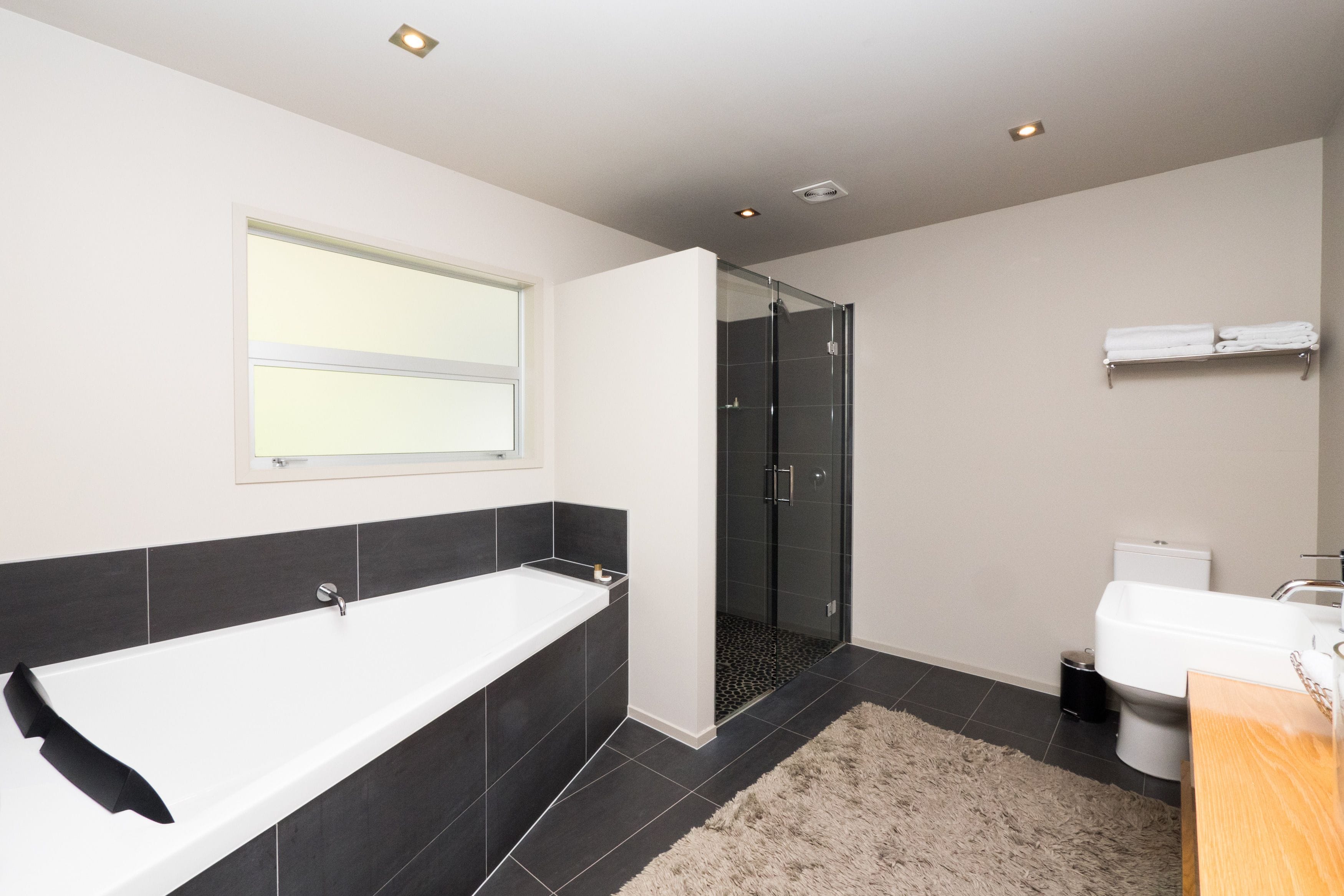 A modern bathroom with a bathtub, toilet, and glass-enclosed shower.