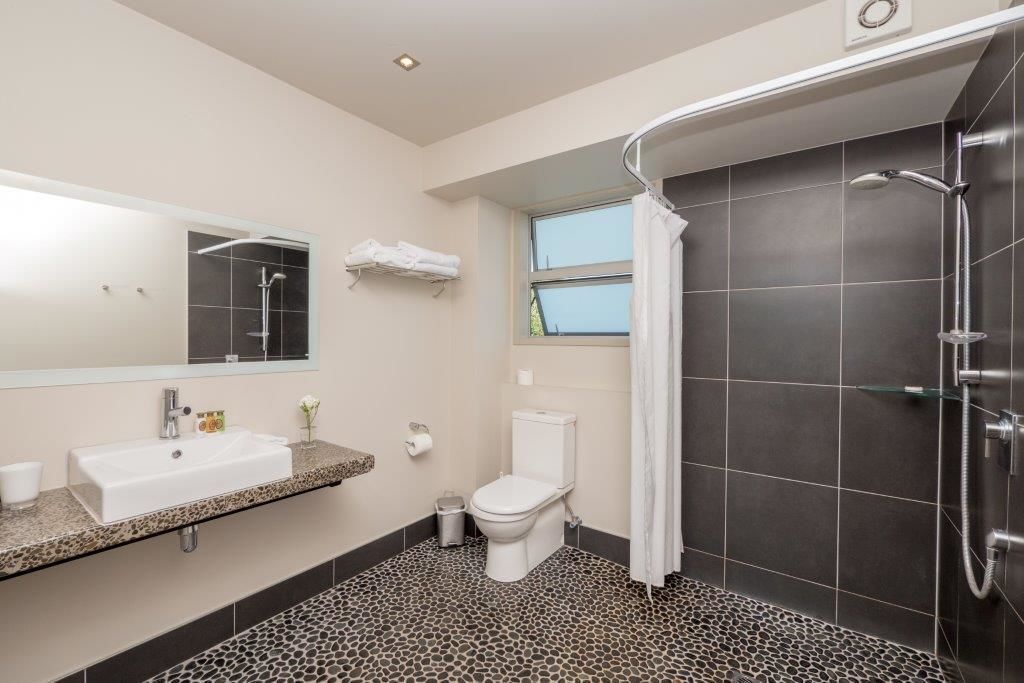 Une salle de bain moderne équipée d’un lavabo, de toilettes et d’une douche.