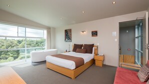 Una habitación de hotel moderna con una cama grande, un área de descanso y vistas al exterior.