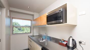 A modern kitchen with a stainless steel microwave, a kettle, and a dish rack.