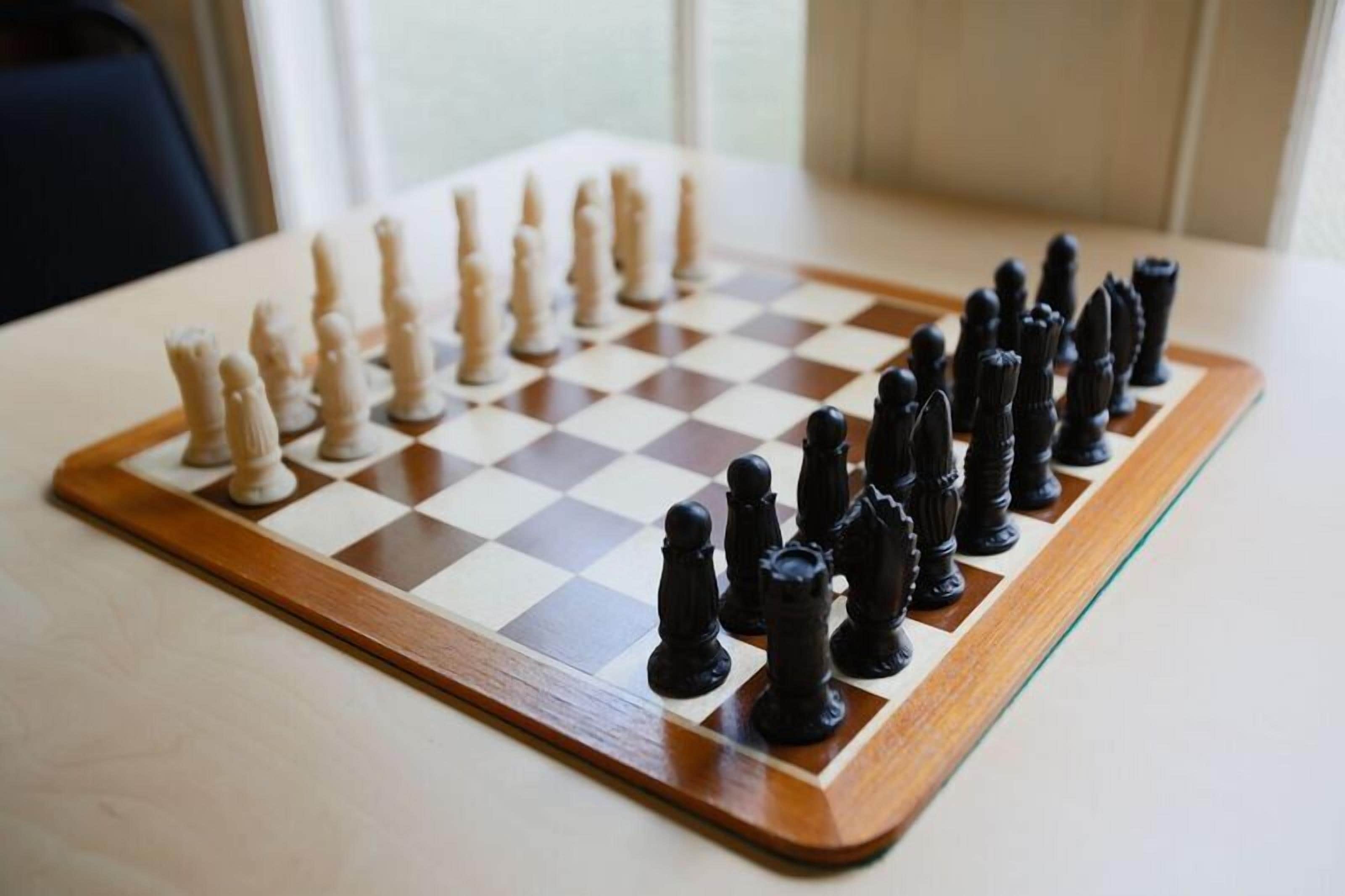 A chessboard on a table with pieces in two colors.