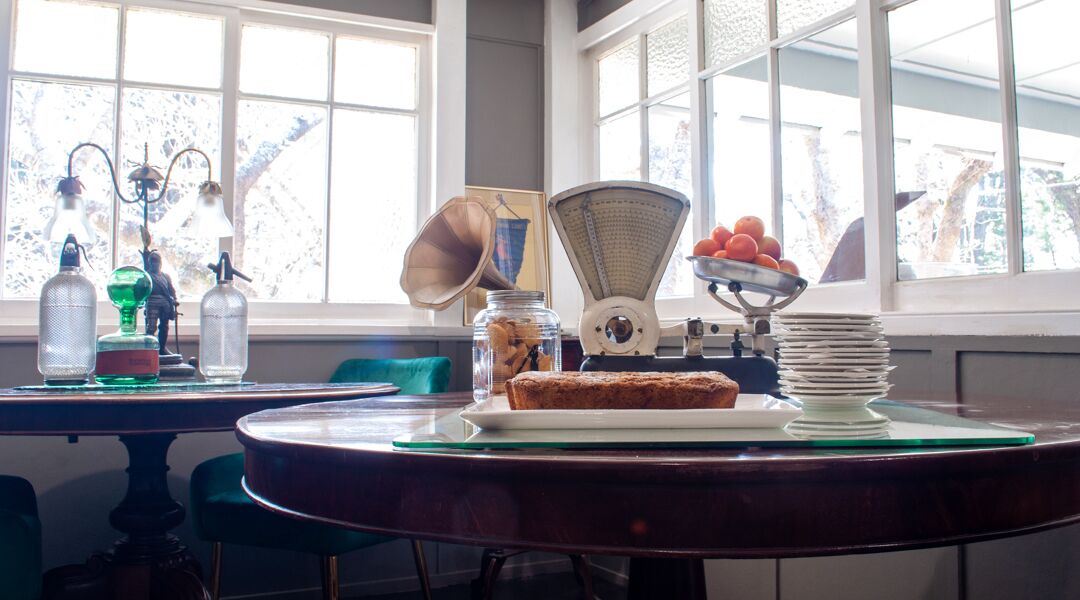 A kitchen with a scale, a bowl of oranges, and a loaf of bread on a table.