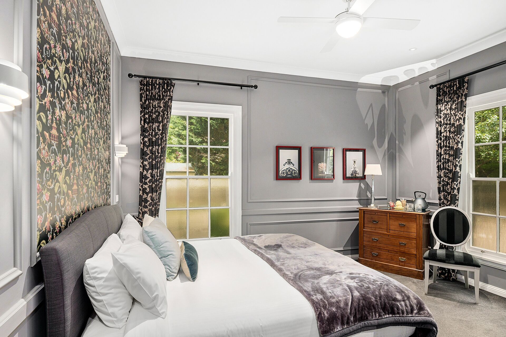 Quarto com cama, cómoda e janela com cortinas.