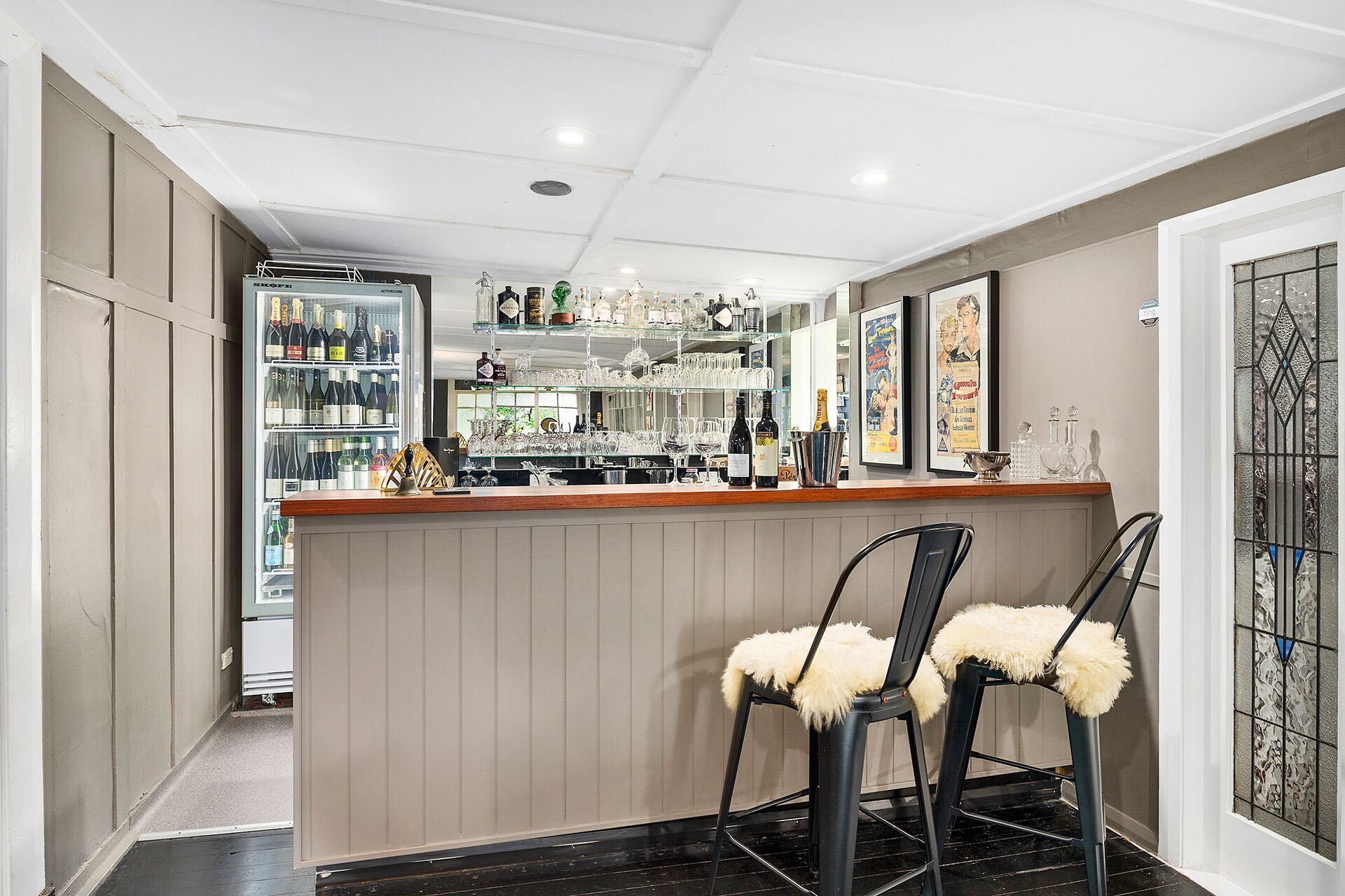 A bar area with a counter, stools, and a wine refrigerator.