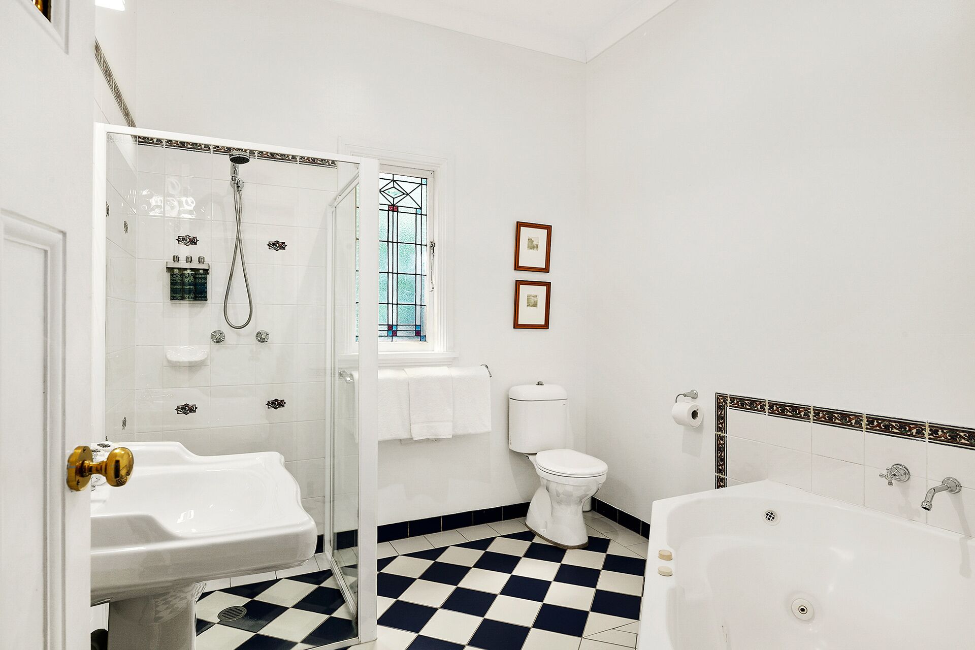Une salle de bain avec un carrelage à motifs géométriques, des toilettes, une baignoire et un espace douche.
