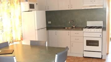 A compact kitchen with white cabinets, a microwave, a sink, and a stove.