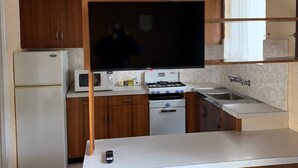 Una cocina con armarios de madera, un refrigerador blanco, un microondas, una estufa y un lavabo.