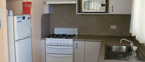 Una cocina funcional con refrigerador, estufa, microondas y lavaplatos.