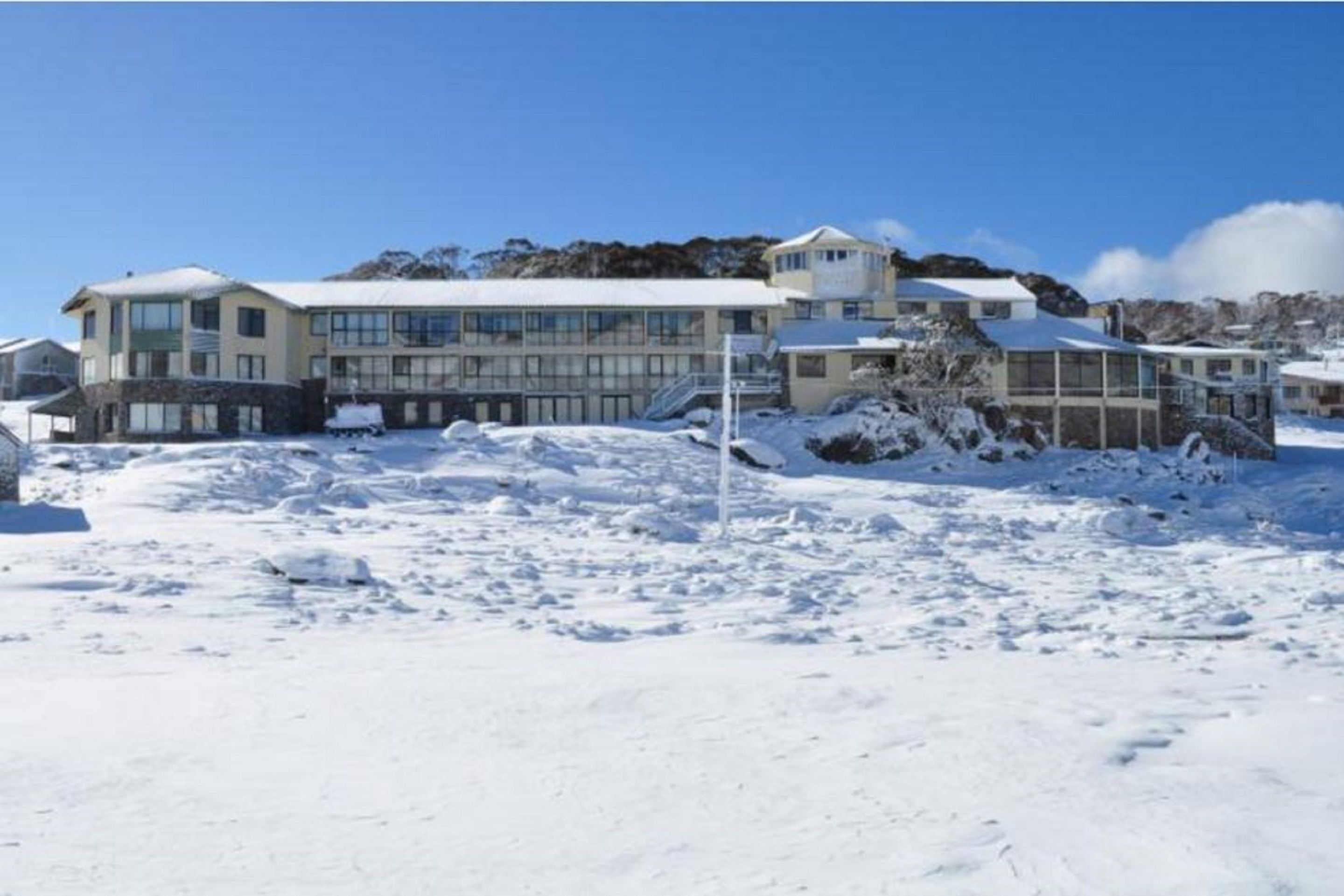 A large, modern building with multiple windows and a prominent tower, surrounded by snow-covered terrain.