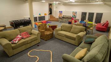 Relax in a spacious room with sofas, an armchair, and a foosball table, surrounded by artwork and a staircase.