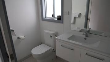 A small, clean bathroom with a toilet, sink, and mirror.
