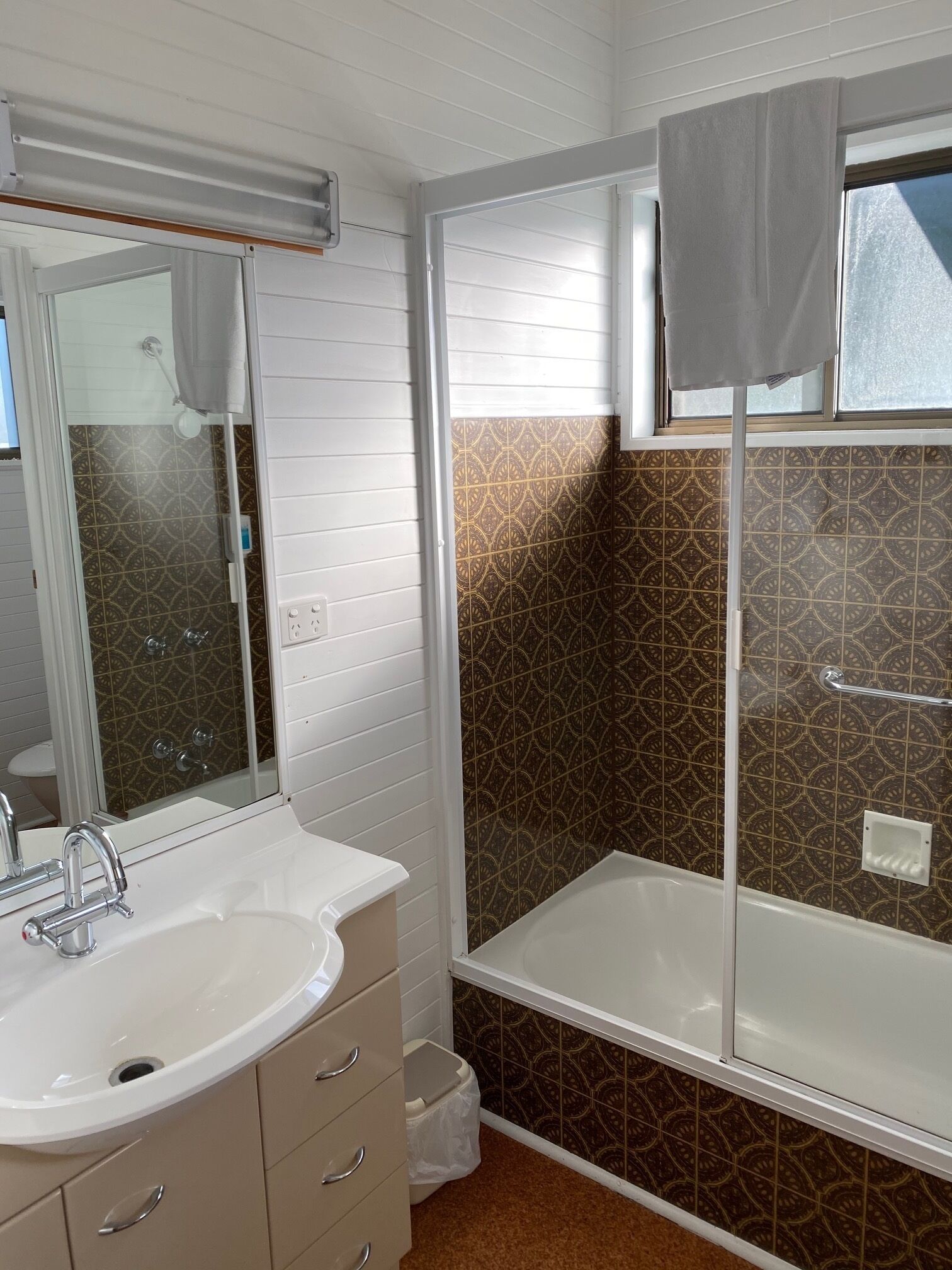A bathroom with a white sink, beige cabinet, and a shower with a glass door.