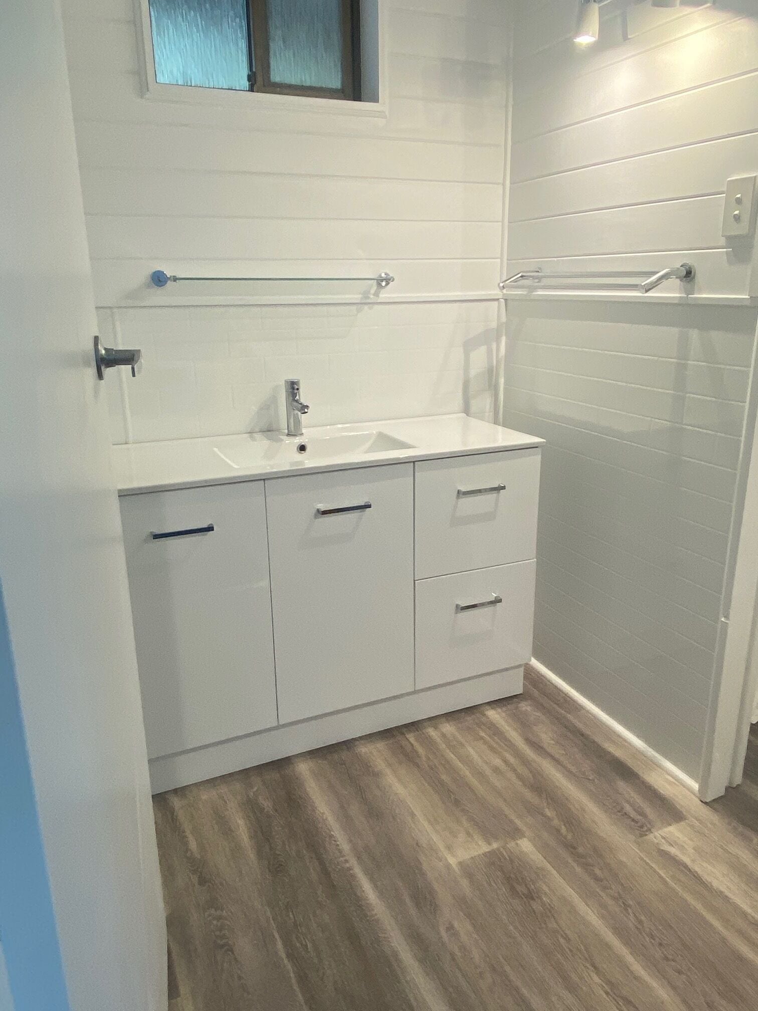 Un baño con tocador blanco, lavamanos y zona de ducha.
