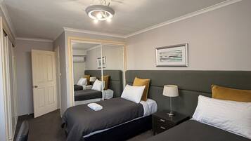Ein Hotelzimmer mit zwei Betten, einem Deckenventilator, einer Tür und einem gerahmten Bild an der Wand.